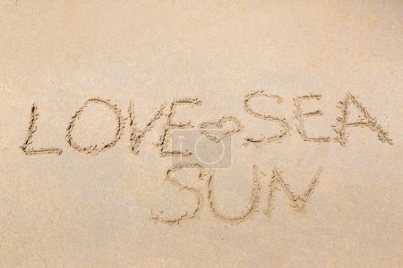 Téléchargez les photos : Le mot amour, mer et soleil est écrit sur une plage de sable - en image libre de droit