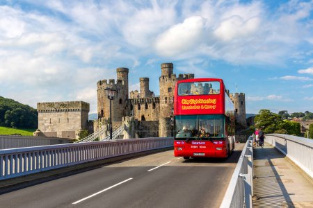 Téléchargez les photos : CONWY, Royaume-Uni - 17 AOÛT 2023 : Bus touristique à deux étages et château de Conwy au Pays de Galles par une belle journée d'été, Royaume-Uni - en image libre de droit
