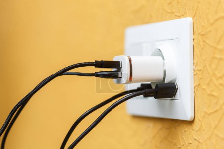 Enchufe eléctrico blanco con puertos USB incorporados y cargador USB con múltiples cables en blanco y negro. Fuente de alimentación y concepto de carga