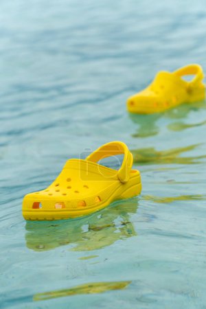 Foto de Zapatillas ligeras de pvh syellow nadando en una superficie de agua. Cómodo concepto de calzado - Imagen libre de derechos