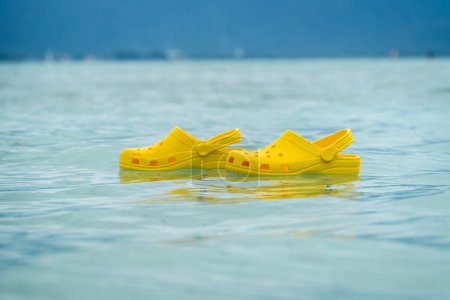 Foto de Zapatillas ligeras de pvh syellow nadando en una superficie de agua. Cómodo concepto de calzado - Imagen libre de derechos