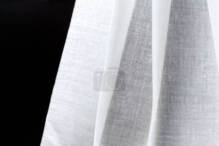Foto de Pliegues de algodón satinado blanco textil transparente sobre un fondo negro. Concepto de diseño textil - Imagen libre de derechos