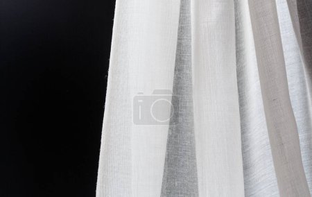 Foto de Pliegues de algodón satinado blanco textil transparente sobre un fondo negro. Concepto de diseño textil - Imagen libre de derechos