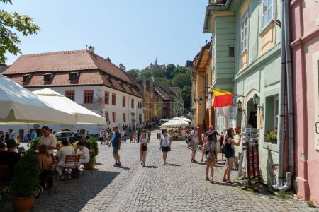 Photo for SIGHISOARA, ROMANIA - august 10, 2019:  People on a square near Casa cu cerbi in Sighisoara, Romania,  in well-preserved old town, listed by UNESCO as a World Heritage Site - Royalty Free Image