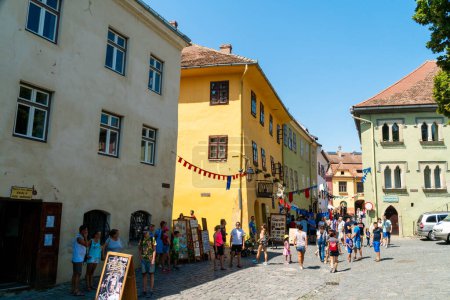 Photo for SIGHISOARA, ROMANIA - august 10, 2019:  People walking by the medieval house, the birthplace of Vlad Dracula in  Sighisoara, Romania,  in well-preserved old town, listed by UNESCO as a World Heritage Site - Royalty Free Image