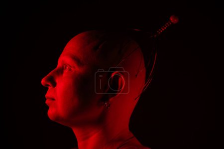 Téléchargez les photos : Un homme sans poil sur la tête en illumination rouge, portrait créatif d'une femme - en image libre de droit