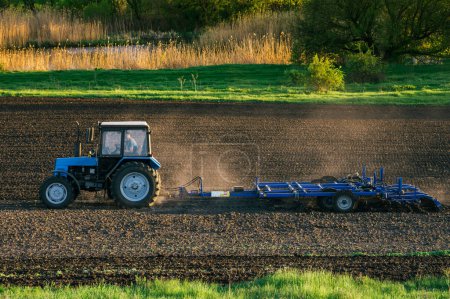 Photo for The tractor cultivates the land in the field in the spring - Royalty Free Image
