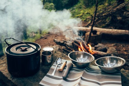 Photo for Camping food cooked on fire, camping food, plates and cauldron, knife and spoon - Royalty Free Image