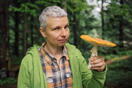 Foto de Mujer en el bosque y recogiendo setas, mosca gorra agárica en sus manos - Imagen libre de derechos