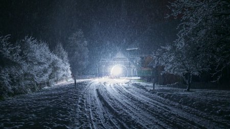 Téléchargez les photos : Chute de neige sur la route la nuit et la lumière de l'équipement de déneigement - en image libre de droit
