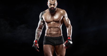 Téléchargez les photos : Boxer homme en gants de boxe sur fond noir. Modèle d'en-tête de site Web sportif. Espace de copie. Athlète des arts martiaux mixtes - en image libre de droit