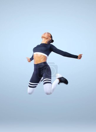 Téléchargez les photos : Attrayant excité fille de remise en forme en sportwear saut de joie isolé sur fond de lumière - en image libre de droit