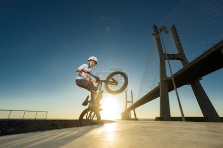 Foto de Un adolescente BMX Racing Rider realiza trucos en un parque de skate en una pista de bombeo - Imagen libre de derechos