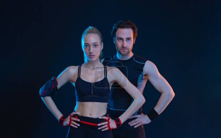 Foto de Download photo for advertising a fitness club in social networks. Fitness Influencers. Fitness couple at home. Cover for sport motivation music. Fit man and woman at the gym on black background. - Imagen libre de derechos