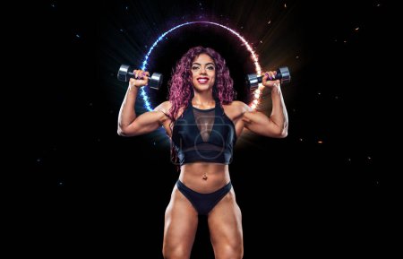 Photo for Modern muslim girl bodybuilder before bodybuilding competition. Fitness concept. Sport and health. Egyptian woman athlete with dumbbells posing on a black background. - Royalty Free Image