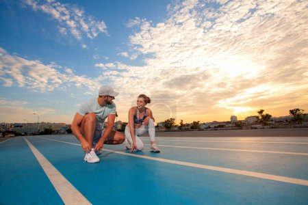 Photo for Athletics couple man and woman getting ready to run. People running on the track field - Royalty Free Image