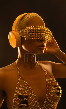 Photo for Girl DJ in neon lights with glasses and headphones. Beautyful woman in violet paint on her face and body. Portrait of sexy TDJ at club party - Royalty Free Image