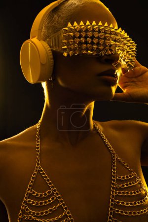 Téléchargez les photos : Jeune DJ en néons avec lunettes et écouteurs. Belle femme en peinture violette sur son visage et son corps. Portrait de sexy TDJ à la fête du club - en image libre de droit