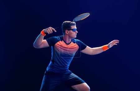 Photo for Badminton player in sport outfit reaching for a shuttle with a racket swing. Studio shoot. - Royalty Free Image