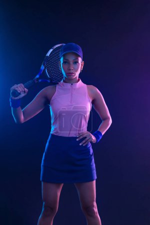 Foto de Jugador de tenis con raqueta. Chica atleta adolescente con raqueta en la cancha con colores de neón. Concepto deportivo. Descargar una foto de alta calidad para el diseño de una aplicación deportiva o sitio de apuestas - Imagen libre de derechos