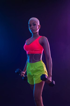 Photo for Sporty fit woman, athlete with dumbbells make fitness exercises on black background. Download cover for music collection for fitness classes. Sports recreation. Beautiful black young woman - Royalty Free Image