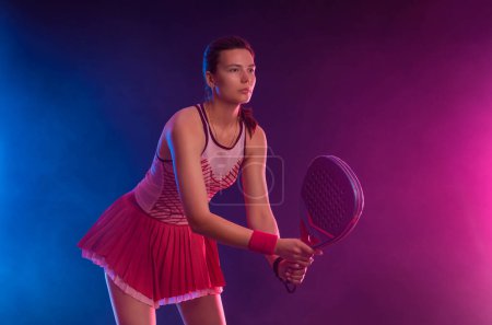 Téléchargez les photos : Joueur de tennis Padel avec raquette. Athlète adolescente avec raquette sur le terrain avec des couleurs fluo. Concept sportif. Téléchargez une photo de haute qualité pour la conception d'une application sportive ou d'un site de paris - en image libre de droit