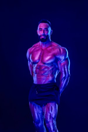 Photo for Athlete bodybuilder in neon colors. Fit man posing on black background. Sports concept. Bodybuilding competition. Download, high resolution, photo - Royalty Free Image