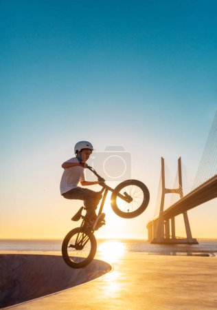 Photo for A teenager BMX Racing Rider performs tricks in a skate park on a pump track - Royalty Free Image