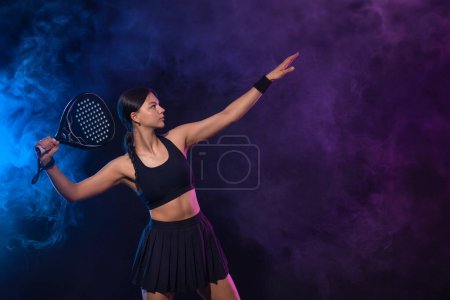 Foto de Tenista de padel con raqueta. Chica atleta adolescente con raqueta en la cancha con colores de neón. Concepto deportivo. Descargar una foto de alta calidad para el diseño de una aplicación deportiva o sitio de apuestas - Imagen libre de derechos