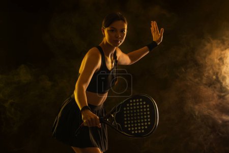 Foto de Tenista de padel con raqueta. Chica atleta adolescente con raqueta en la cancha con colores de neón. Concepto deportivo. Descargar una foto de alta calidad para el diseño de una aplicación deportiva o sitio de apuestas - Imagen libre de derechos