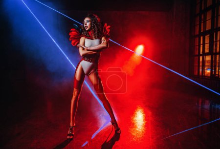 Téléchargez les photos : Jeune femme danseuse posant à l'intérieur sombre avec des lasers - en image libre de droit