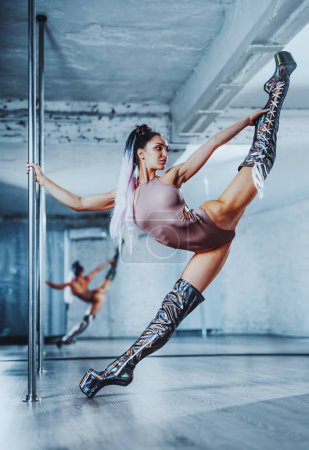 Photo for Young sexy slim woman with long legs pole dancing - Royalty Free Image