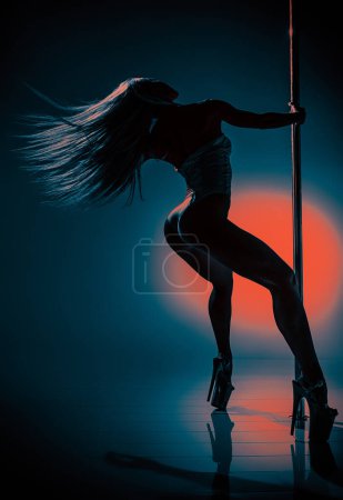 Foto de Joven mujer bailando polo sobre fondo oscuro con contraste círculo rojo de luz - Imagen libre de derechos