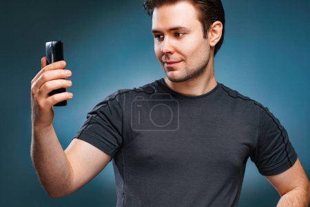 Foto de Young handsome man taking selfie portrait on gray wall background - Imagen libre de derechos