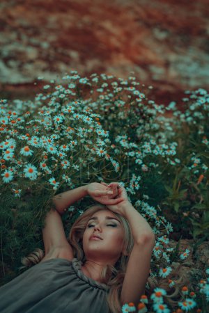 Téléchargez les photos : Jeune femme rêveuse portrait sur champ d'été avec des camomilles - en image libre de droit