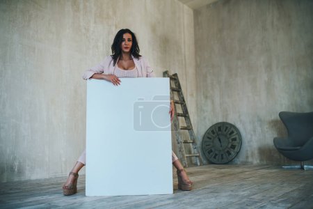 Téléchargez les photos : Jeune femme debout avec tableau blanc à l'intérieur blanc doux - en image libre de droit