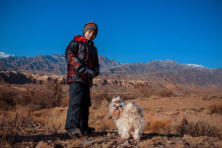 Foto de Niño con cámara en las manos y shih tzu perro de pie sobre el fondo de las montañas - Imagen libre de derechos