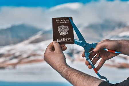 Foto de Hombre corte pasaporte ruso en el fondo de las montañas, concepto de inmigración - Imagen libre de derechos