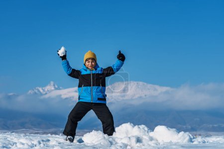 Téléchargez les photos : Enfant posant sur fond de montagne à la saison d'hiver - en image libre de droit