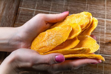 Photo for Young woman holding in hands dried mango on table background - Royalty Free Image