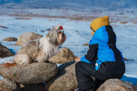 Foto de Niño con shih tzu perro mirando el uno al otro en invierno paisaje fondo - Imagen libre de derechos