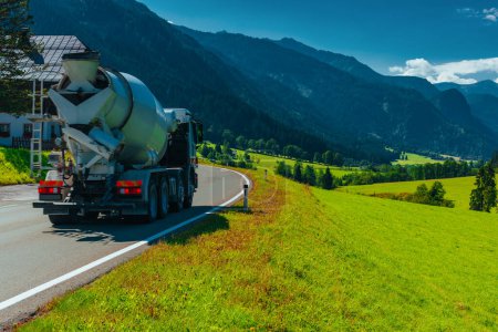 Téléchargez les photos : Conduites de camions bétonnières sur une belle route dans les Alpes - en image libre de droit