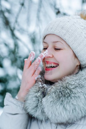 Foto de Retrato de mujer joven feliz en ropa de invierno caliente con nieve en la nariz - Imagen libre de derechos