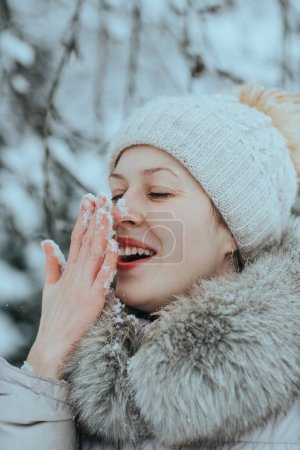 Foto de Retrato de mujer joven feliz en ropa de invierno caliente con nieve en la nariz - Imagen libre de derechos