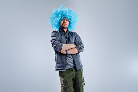 Foto de Joven posando en una peluca de payaso azul sobre fondo gris - Imagen libre de derechos