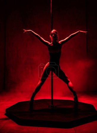 Foto de Bailarina de polo joven posando en estudio, luz roja dramática - Imagen libre de derechos