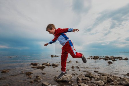 Foto de Niño balanceándose en la roca en la orilla del lago - Imagen libre de derechos