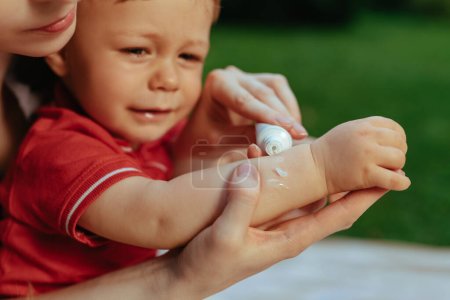 Photo for Mother puts cream on baby's hand in summer - Royalty Free Image