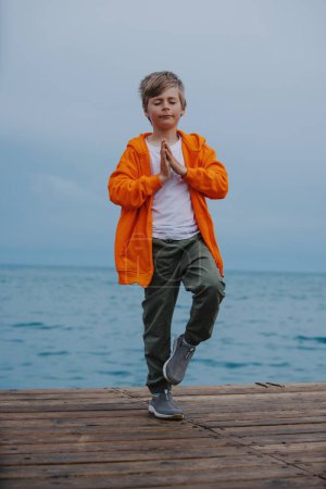 Téléchargez les photos : Garçon debout en méditation pose au bord de la mer - en image libre de droit