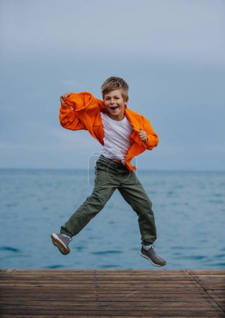 Foto de Niño feliz saltando en la orilla del mar - Imagen libre de derechos